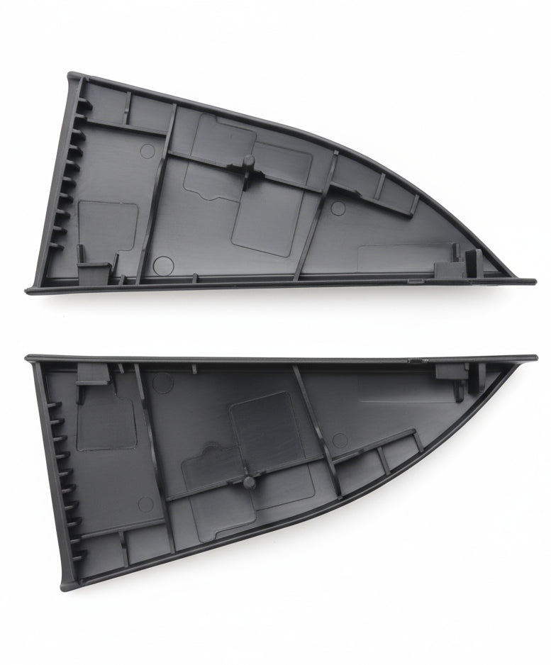 Two black plastic triangular parts on a textured surface with a blurred background
