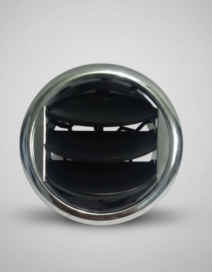 Close-up of a car air vent with a metallic rim on a textured surface.