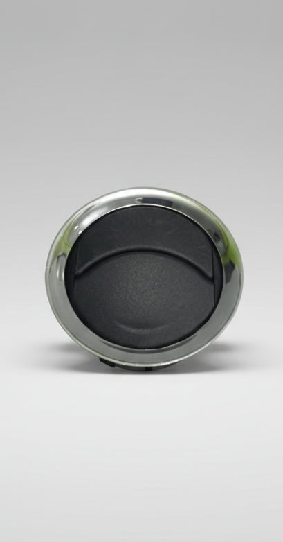 Round metallic object with black center on a light gray background