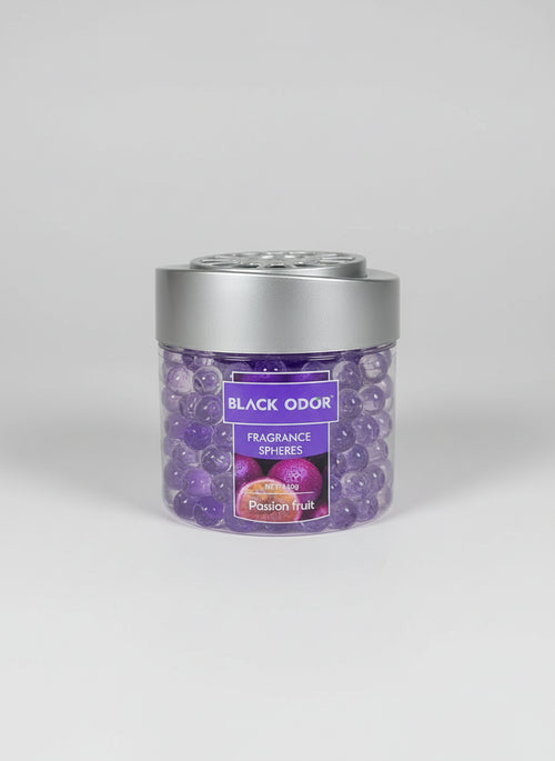 Hand holding a container of Black Odor Fragrance Spheres with a blurred store background