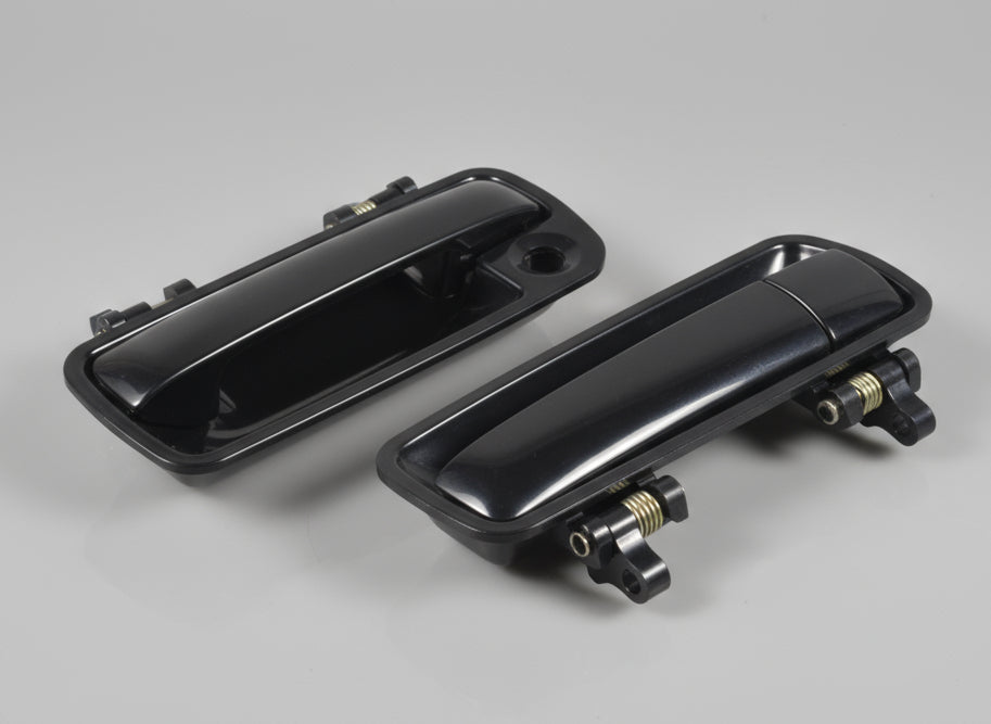 Two black car door handles on a cardboard box with visible branding.