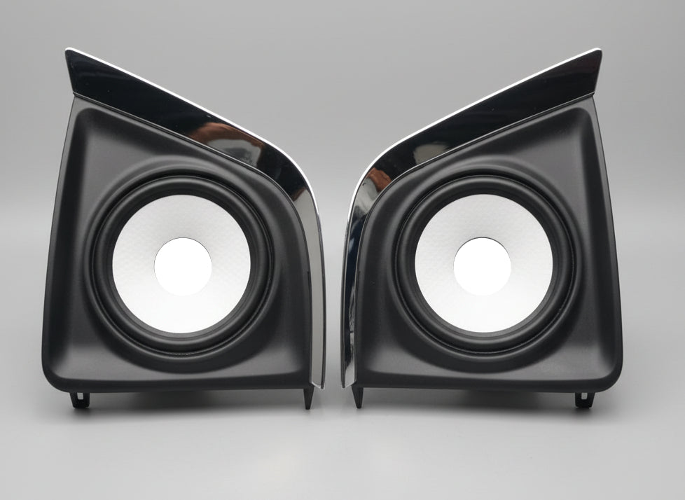 Pair of black car speakers with chrome trim on a white background