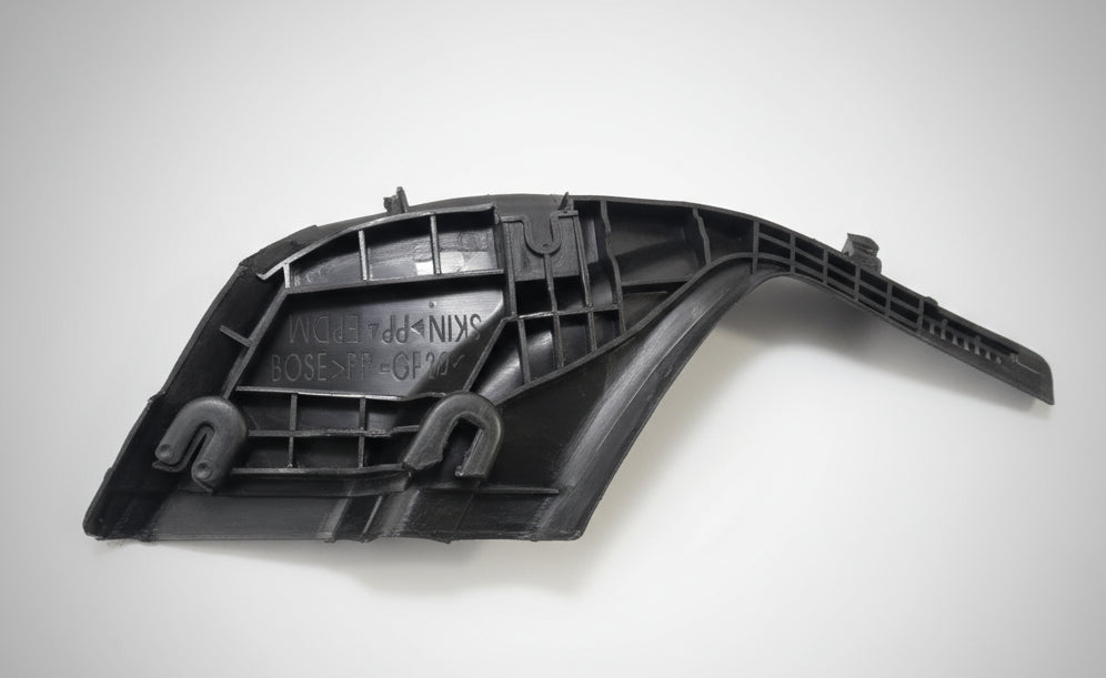 Black plastic car part on a white surface