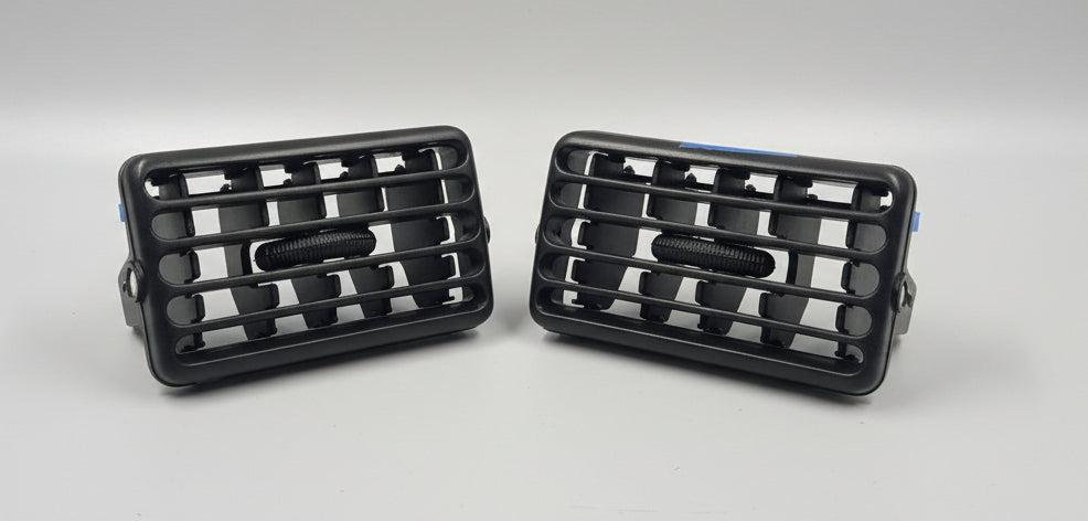 Two black grille covers on a white surface
