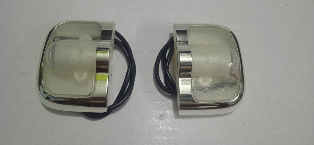 Two metallic light fixtures with clear lenses on a white background