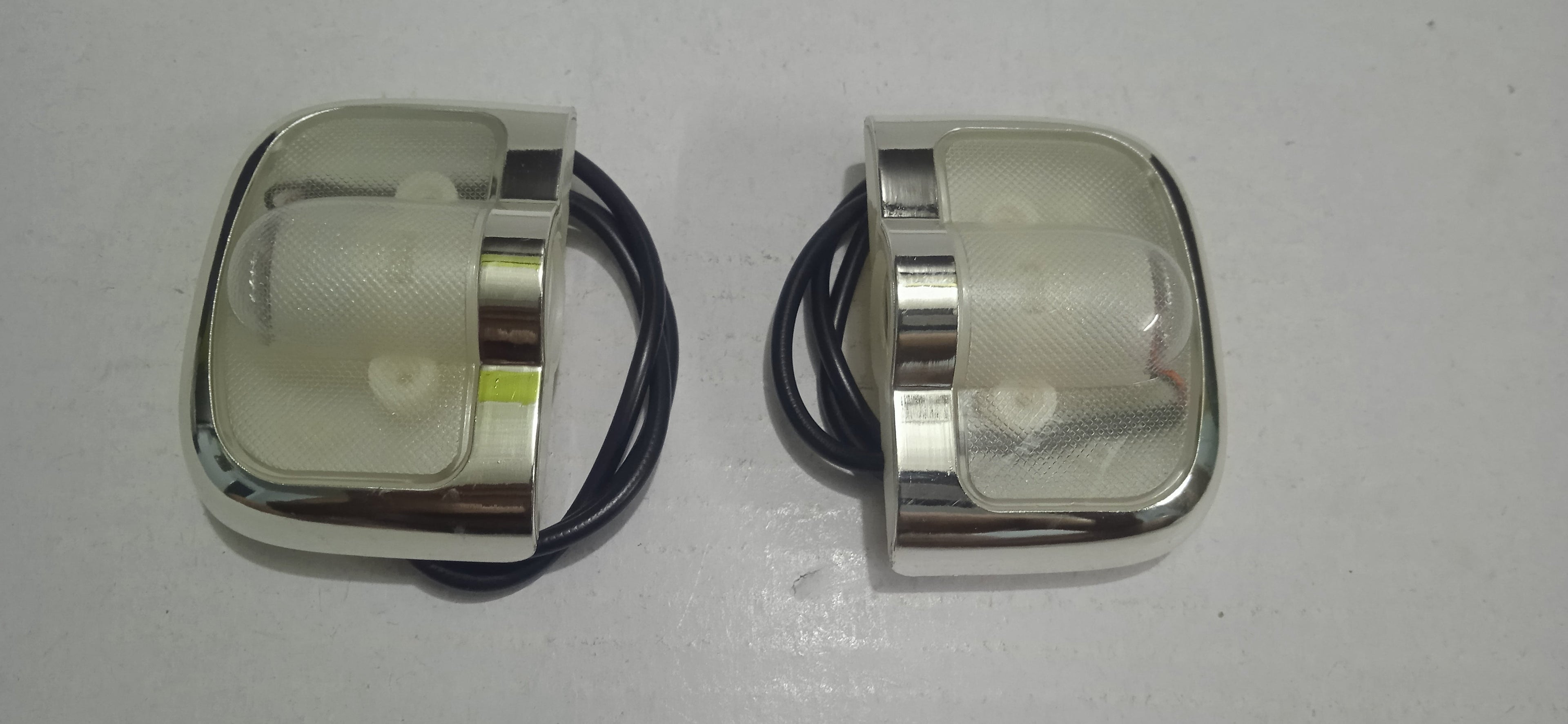 Two metallic light fixtures with clear lenses on a white background