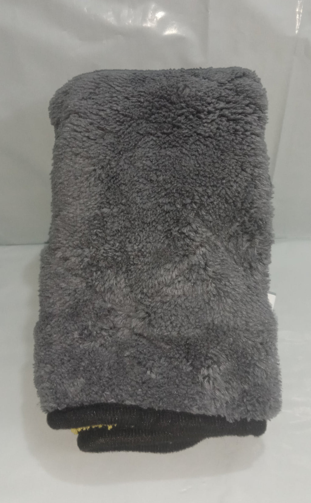 Gray towel folded on a white surface with a clear plastic bag in the background