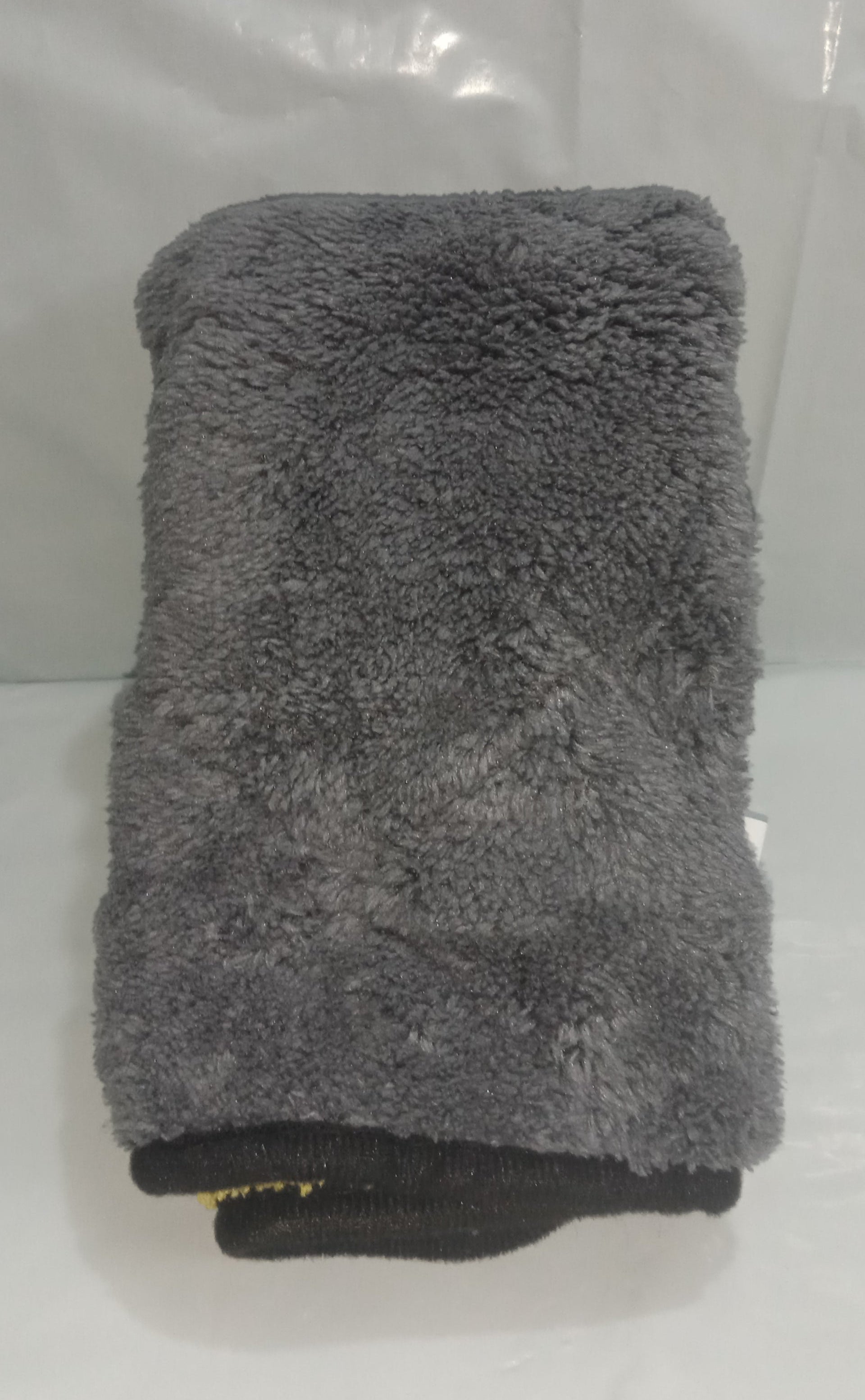 Gray towel folded on a white surface with a clear plastic bag in the background