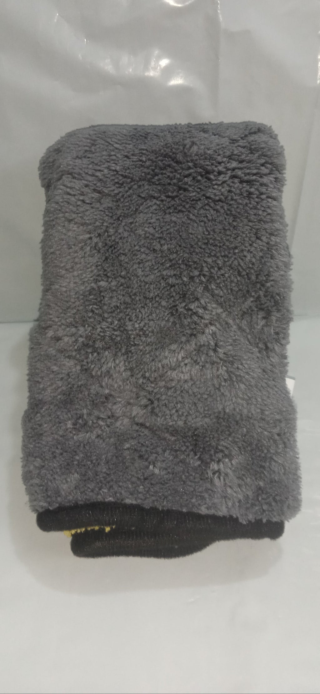 Gray towel folded on a white surface with a clear plastic bag in the background