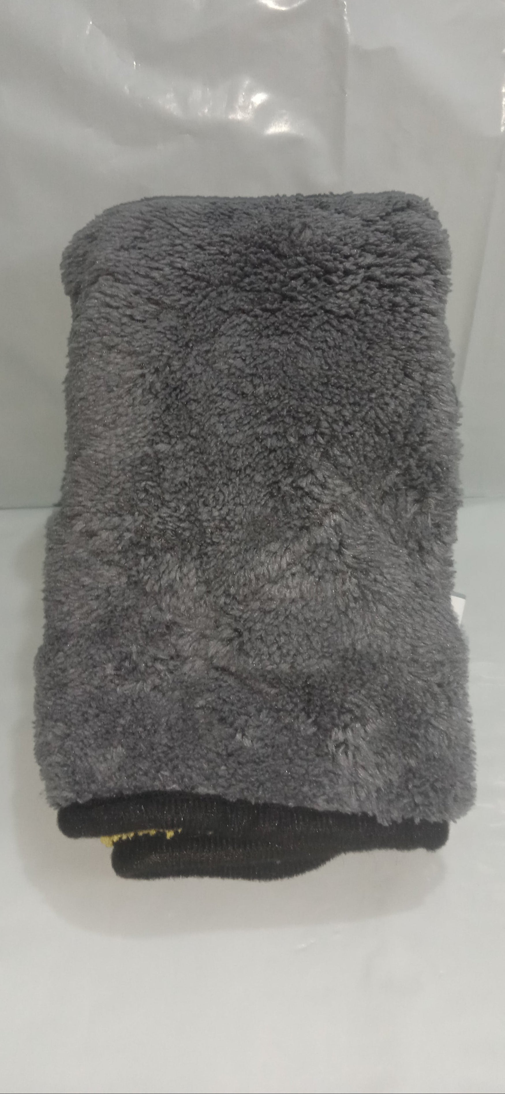 Gray towel folded on a white surface with a clear plastic bag in the background
