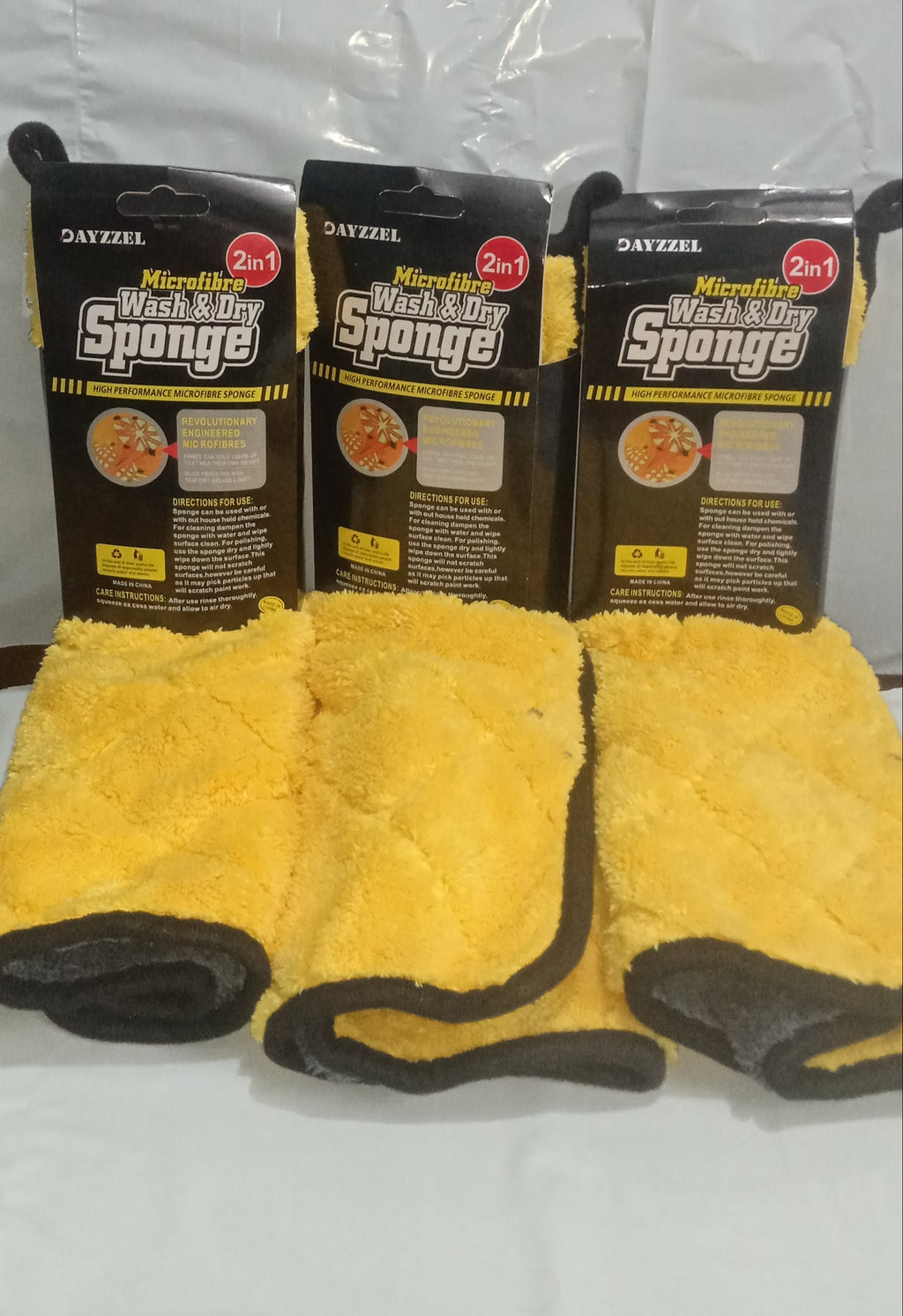 Three packages of microfiber sponges with yellow cloths on a white background