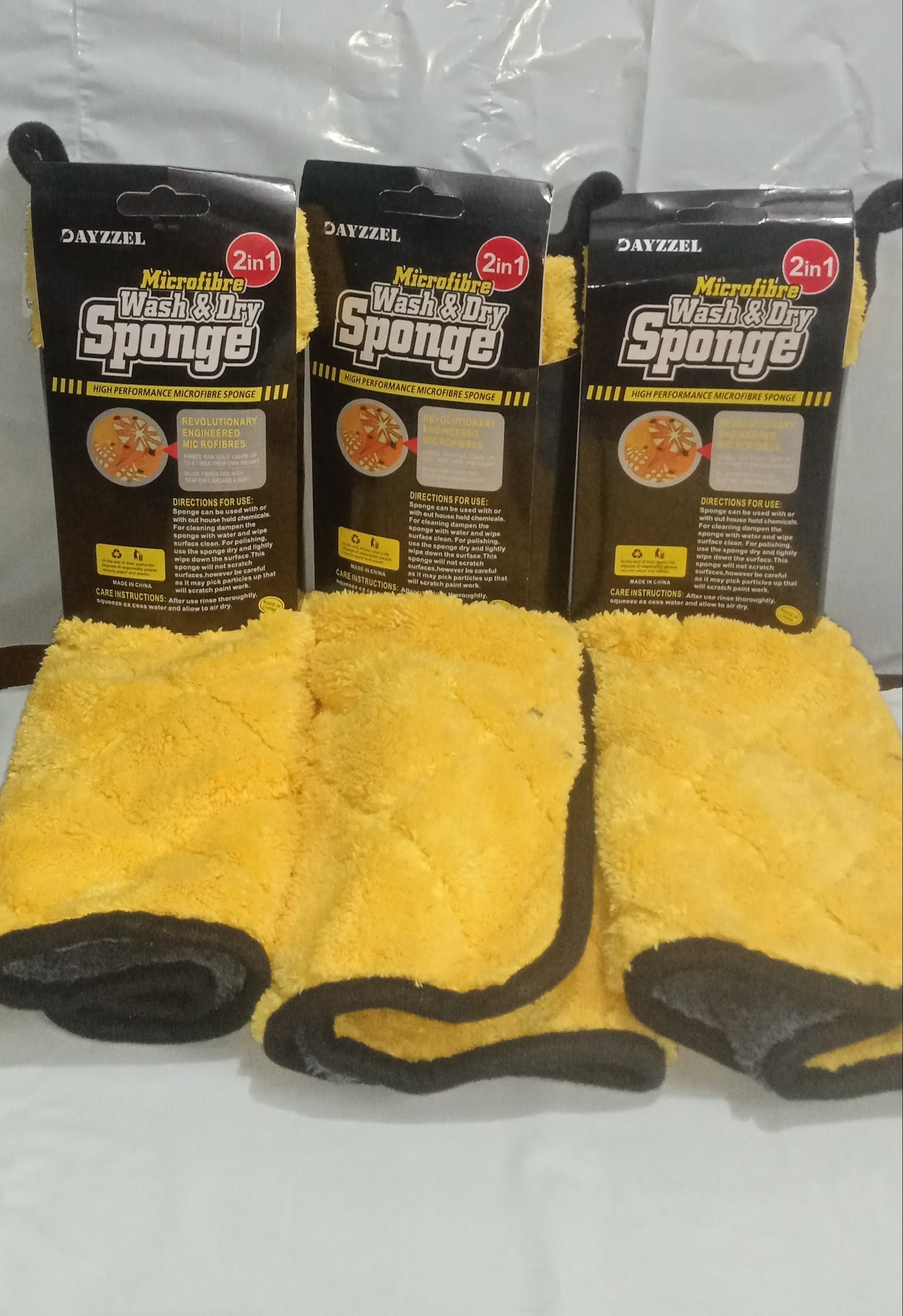 Three packages of microfiber sponges with yellow cloths on a white background