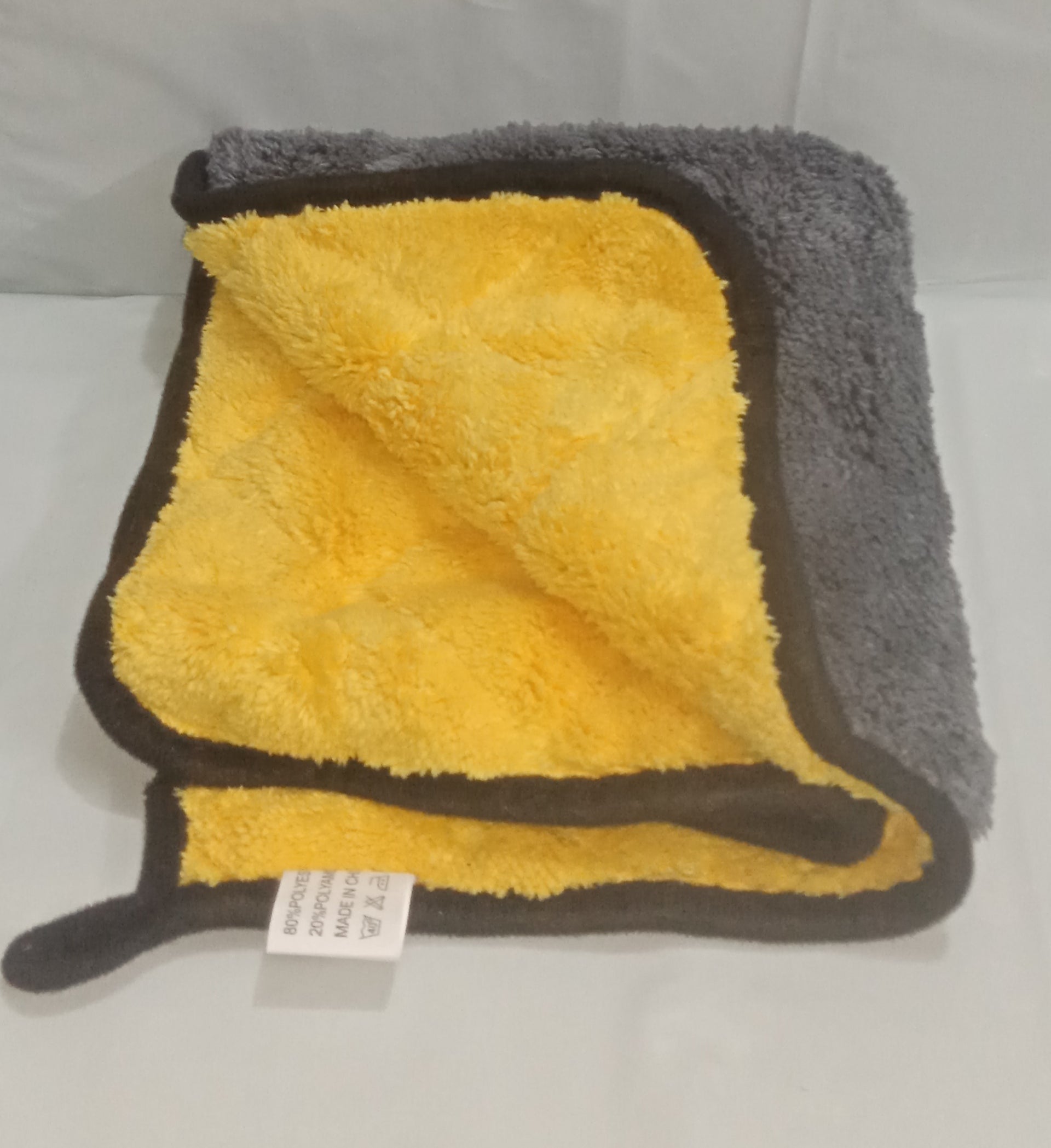 Folded yellow and gray towel on a white surface