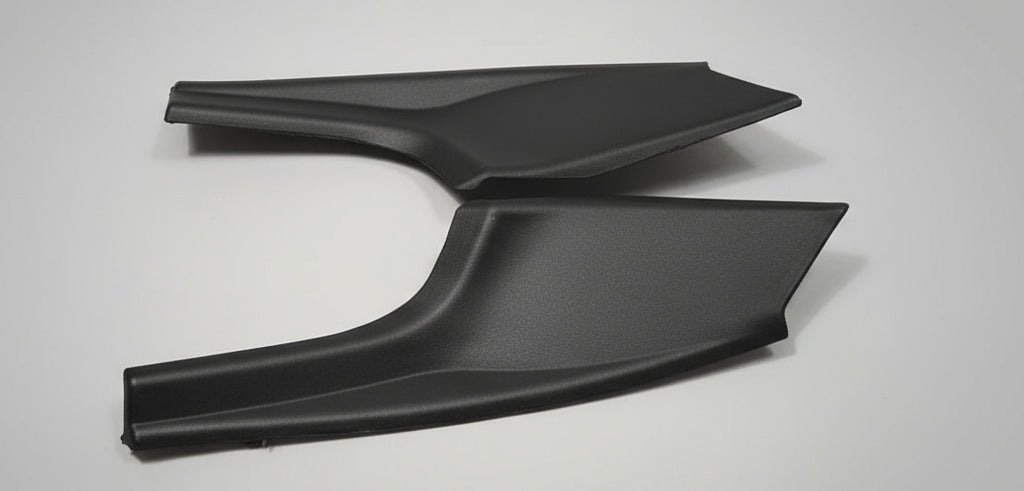 Two black car mud flaps on a white box with a gray floor background