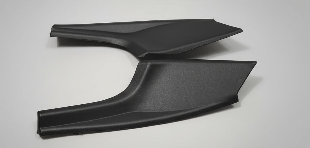 Two black car mud flaps on a white box with a gray floor background