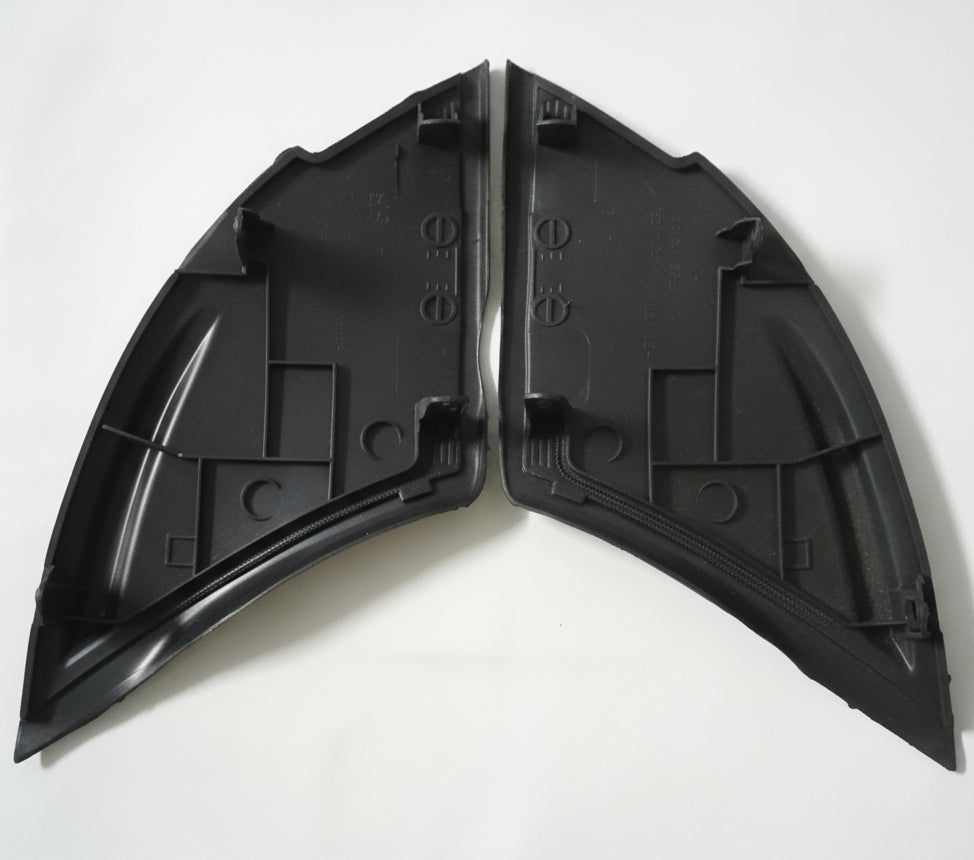 Two black plastic car fender sections on a white background