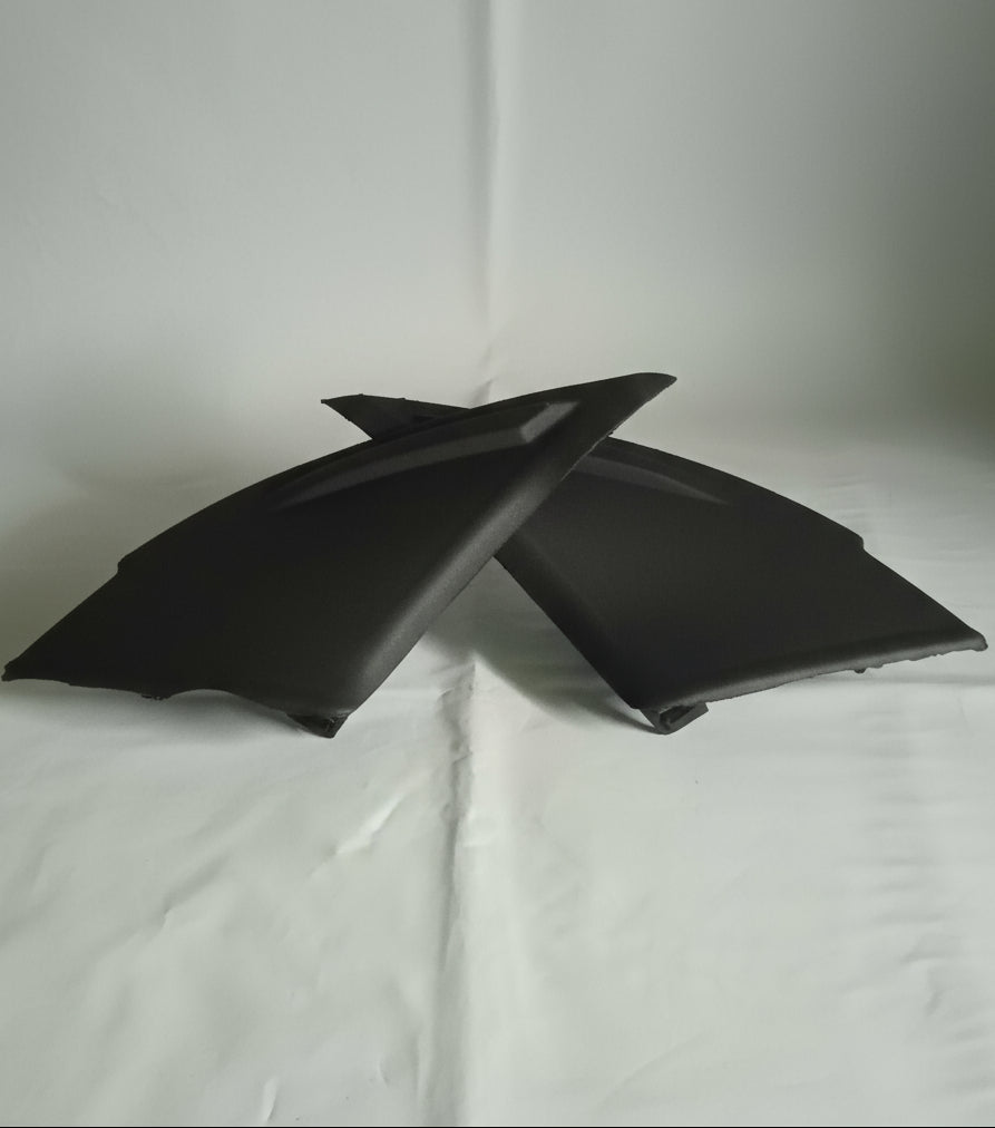 Two black car side mirrors on a white surface