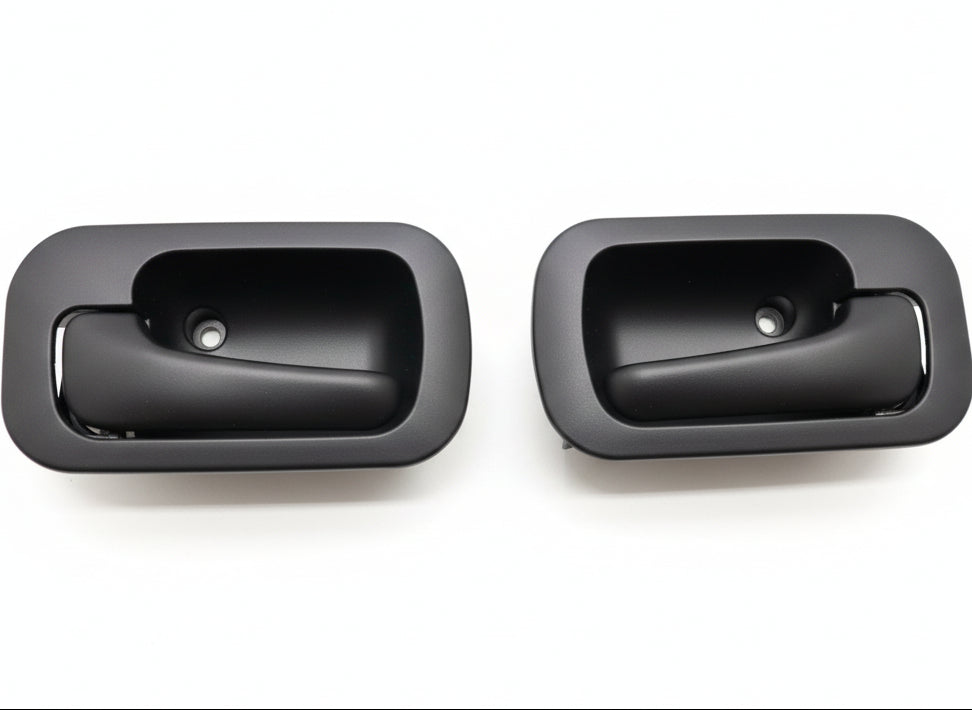Two black interior car door handles on a white surface