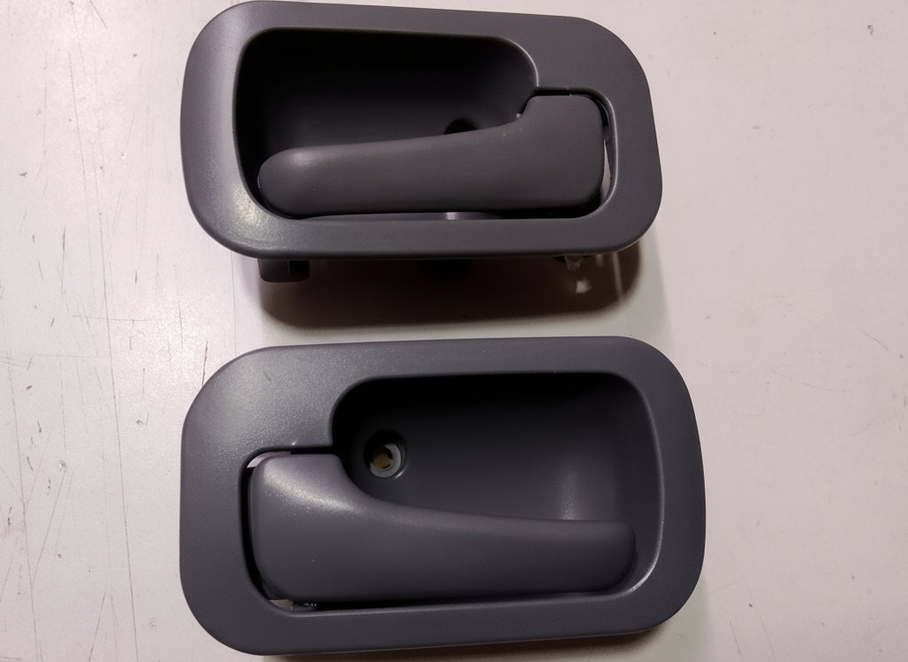 Two black interior car door handles on a gray surface