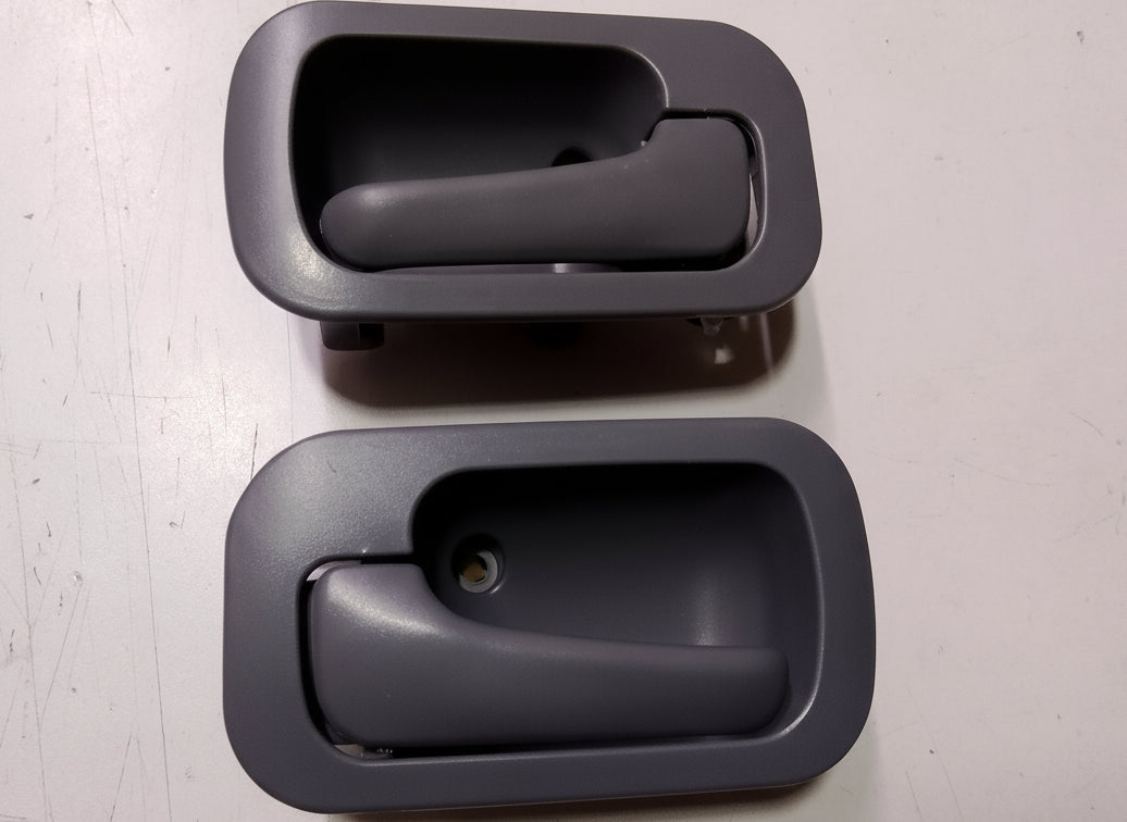 Two black interior car door handles on a gray surface