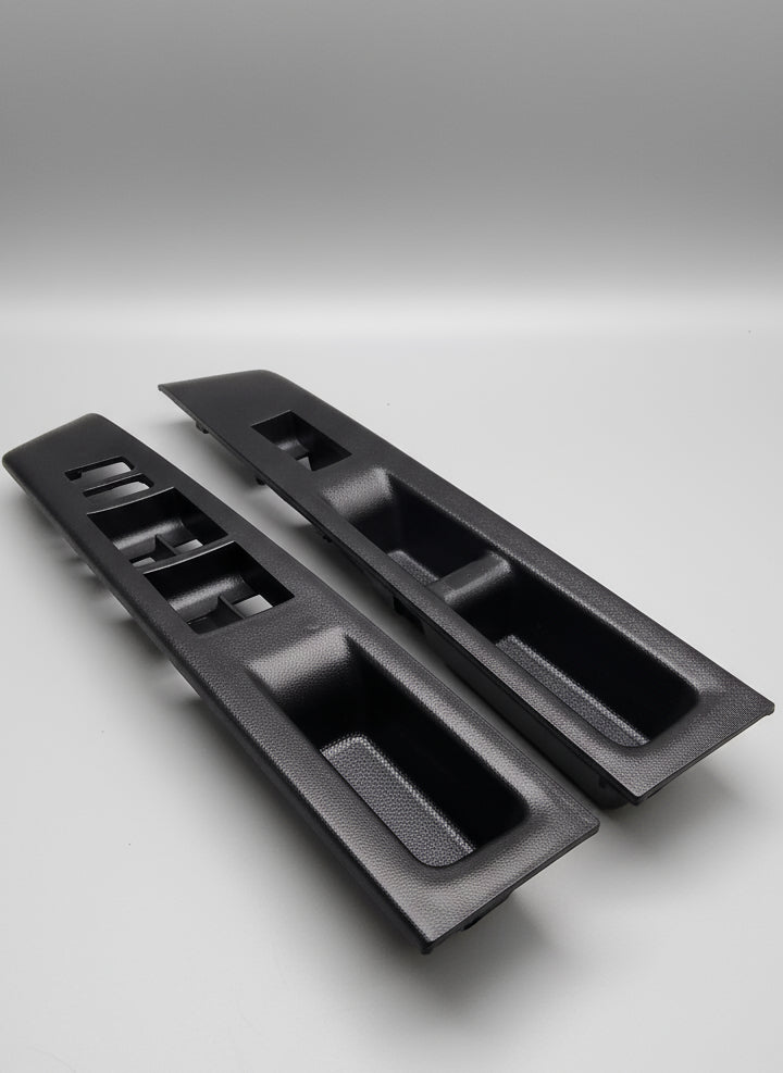 Two black car interior door panels on a stone surface