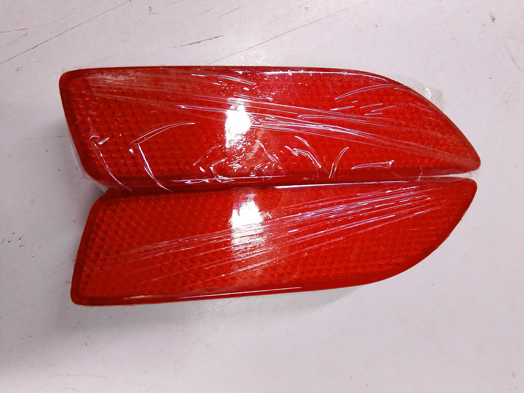 Two red car lights wrapped in plastic on a white surface