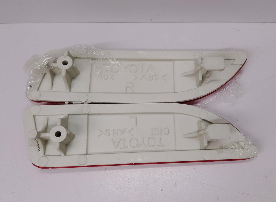 Two white plastic car parts with Toyota branding on a light gray background