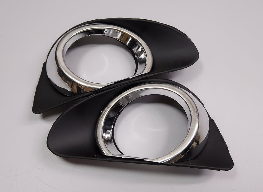 Pair of car fog lights with black casings and chrome rims on a white background