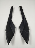 Two black plastic car parts on a light gray floor.