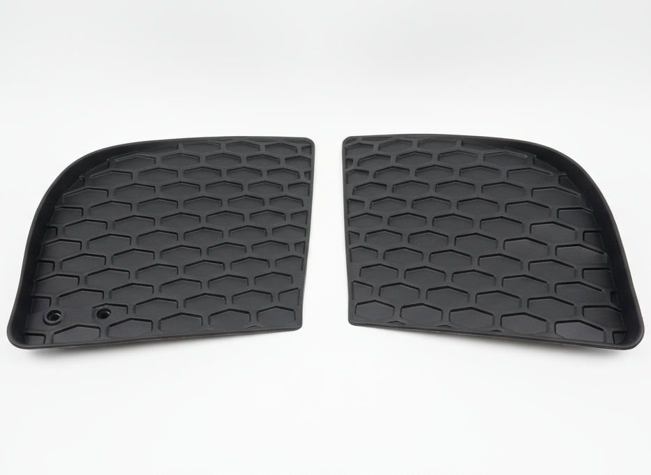Two black honeycomb-patterned car mats on a tiled floor.