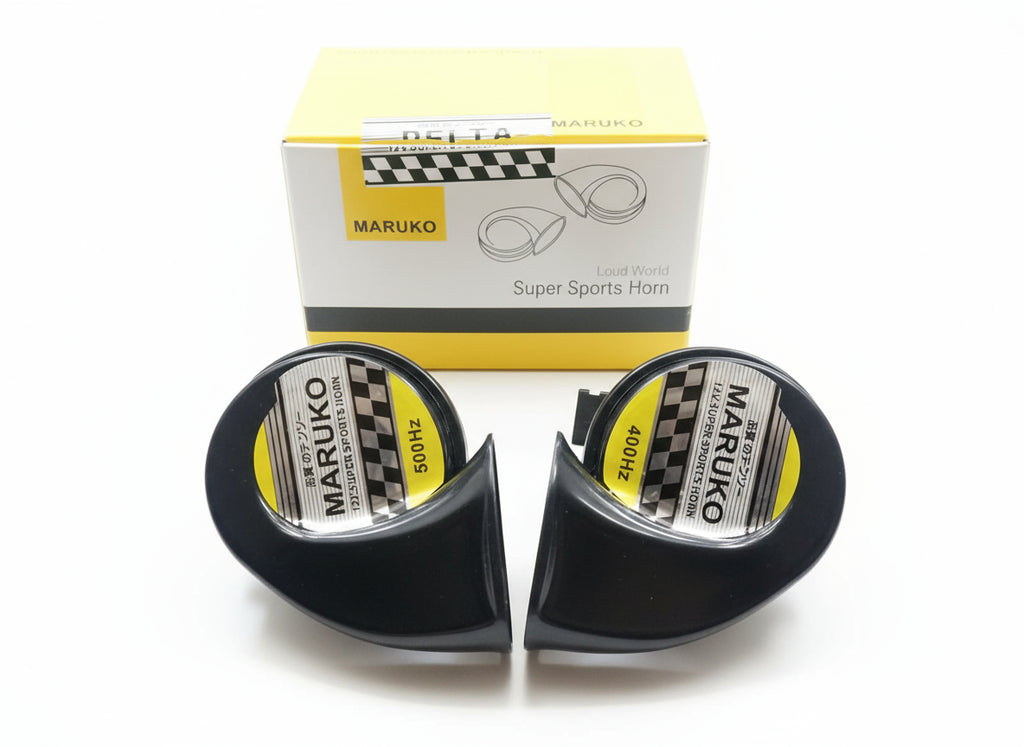 Two black Maruko Super Sports Horns on a wooden surface with their packaging.