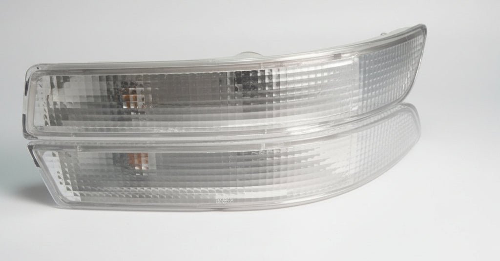 Two car side mirrors on a white surface with a dark background