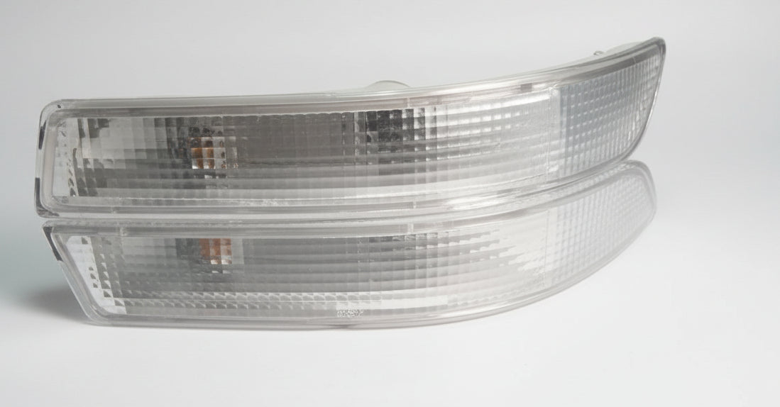 Two car side mirrors on a white surface with a dark background