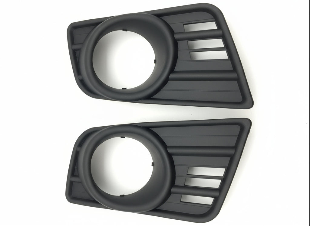 Two black plastic automotive parts on a wooden surface
