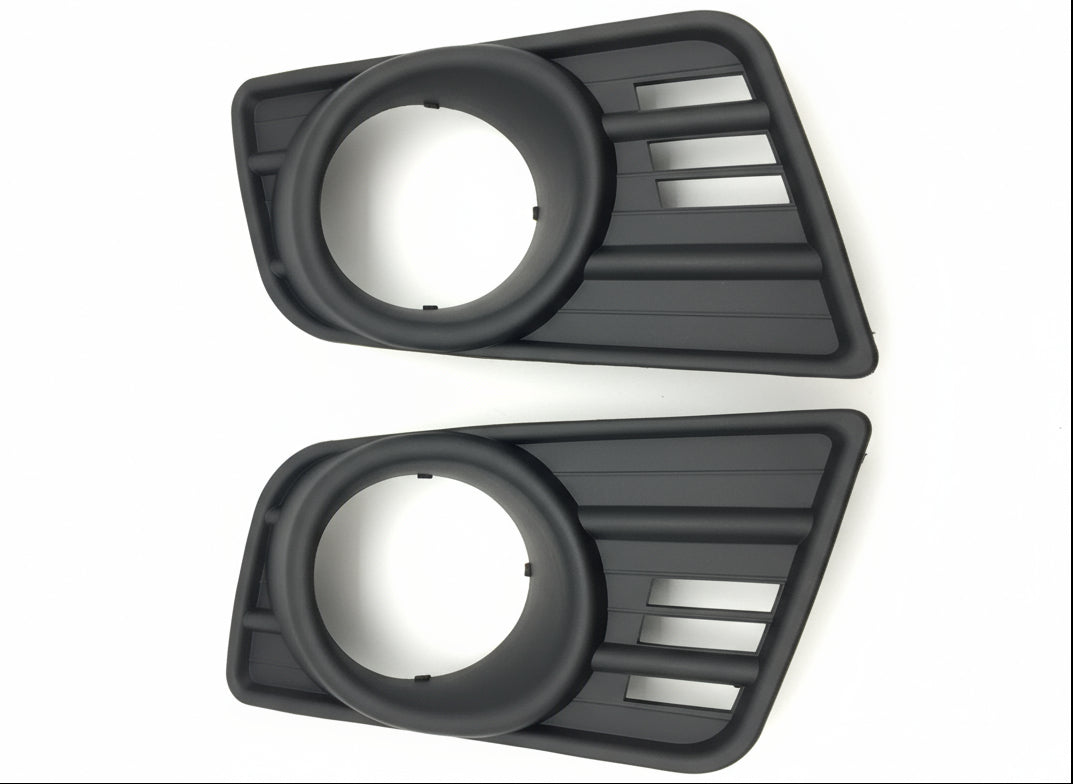 Two black plastic automotive parts on a wooden surface