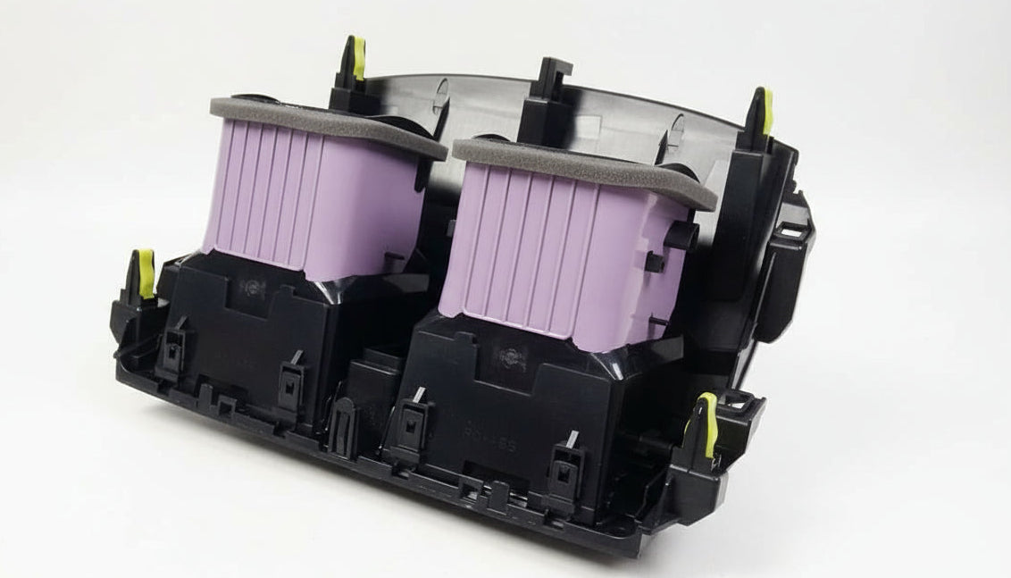 Close-up of a printer cartridge holder with two black cartridges inside, on a textured surface.